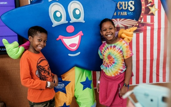 Kids taking a picture with Sparkle, the star-shaped mascot of Children's Minnesota